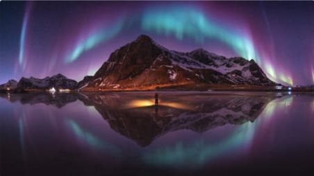 Foto panorama dramatis yang menampilkan Cahaya Utara (Aurora Borealis) membentuk lengkungan langit yang sempurna di atas puncak gunung berselimut salju, karya fotografer asal Bangkok, Wutimet Bunyasirisith, terpilih sebagai pemenang The Pano Awards Southeast Asia Open Photographer of the Year 2026.